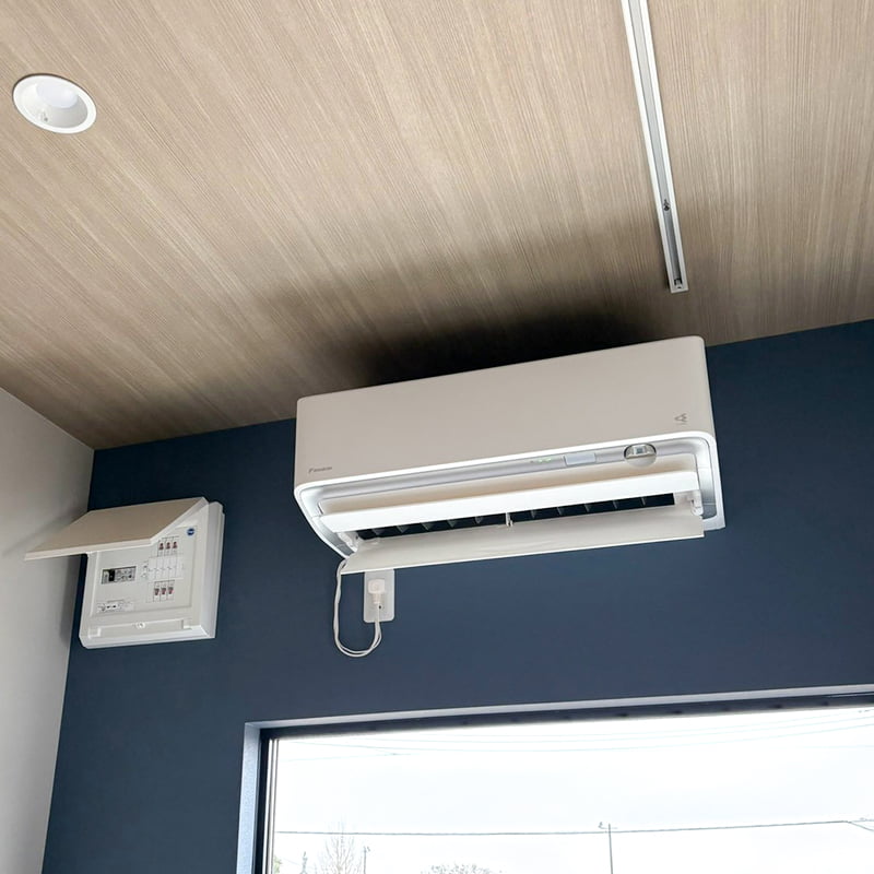 壁付けエアコンと分電盤を取り付けた室内